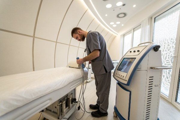 Technician prepares shockwave device for treatment session in clinic (ID#2)