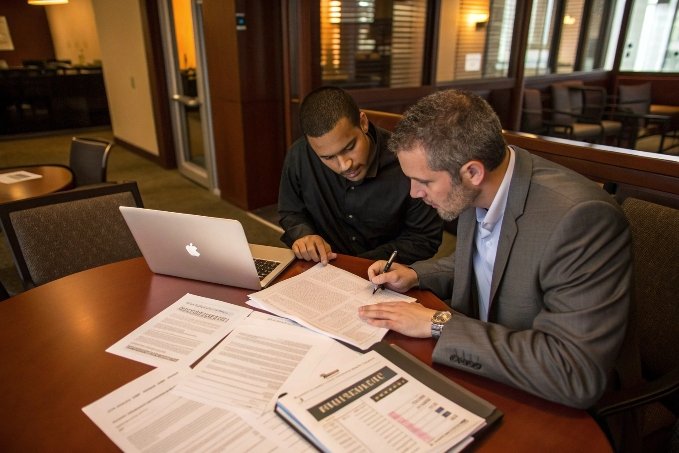 Dos profesionales revisan contratos durante reunión de proveedores (ID#3)