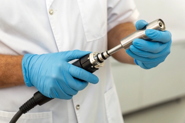 Professional close-up of technician wearing blue gloves assembling a precision laser handpiece (ID#4)