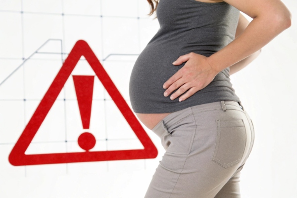 Stark safety illustration: a pregnant woman with lower back pain and a red warning triangle symbol (ID#4)